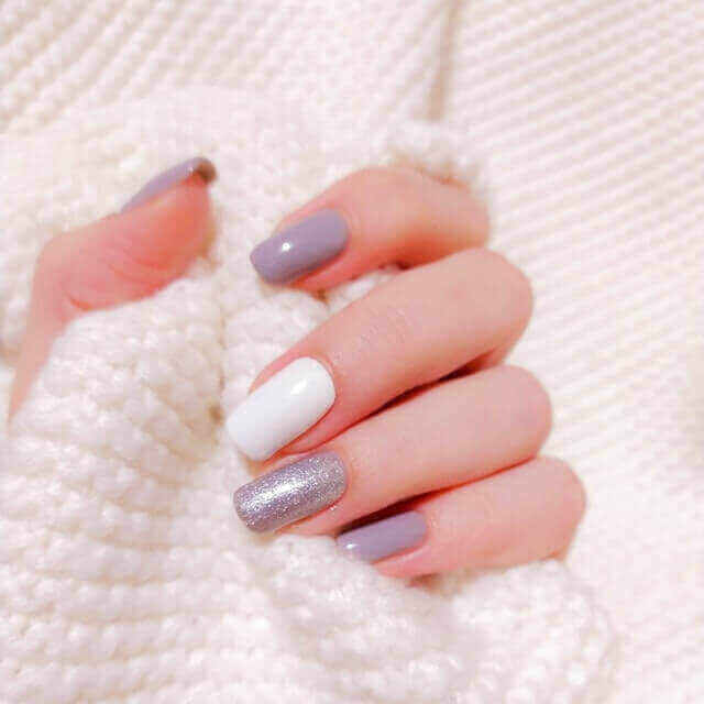 Hand with purple and white nail design holds a white sleeve