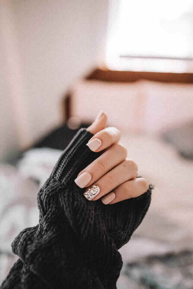 Hand with pink nails with zircons holds black a sleeve
